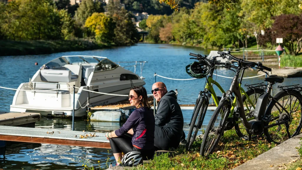 Couple faisant une pause au bord de la ViaRhôna vers Charmes-sur-Rhône, auprès de leurs vélos à assistance électrique, en automne