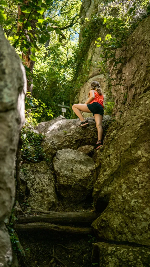 Adolescente grimpant des rochers au bois de Païolive