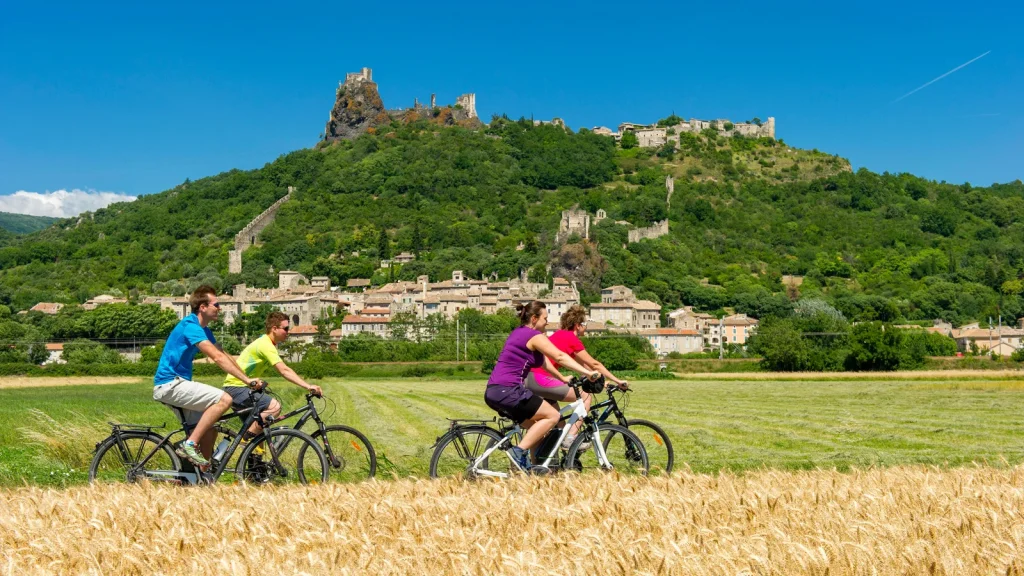 Groupe d'amis roulant à vélo devant le village de caractère de Rochemaure, en été