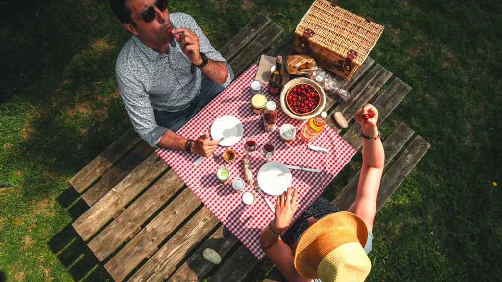 Couple partageant un pique-nique avec des produits "Goûtez l'Ardèche" en été