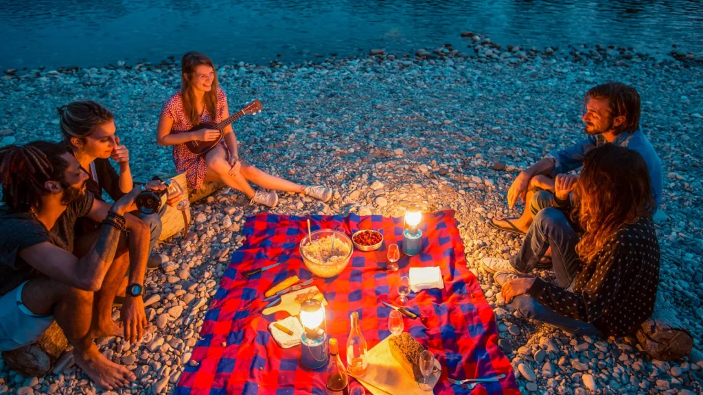 Groupe d'amis profitant d'un pique-nique au bord de l'eau, en soirée