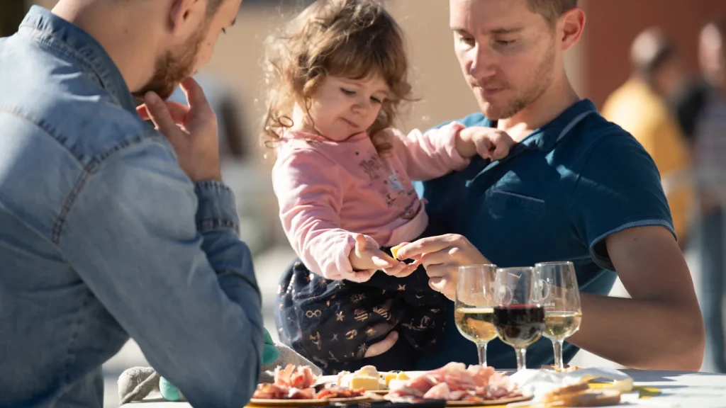 Wine tasting between friends with a little girl picking at a piece of cheese