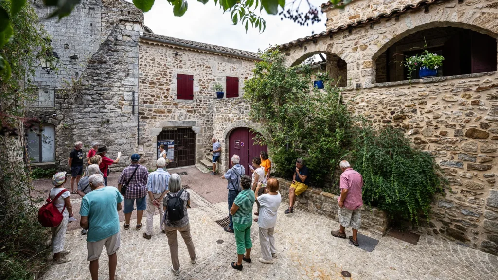 Groupe suivant une visite guidée du village de caractère de Vinezac, en été