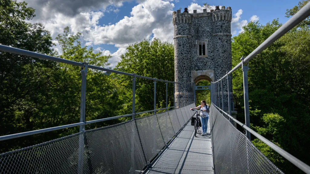 Femme passant, avec son vélo sur la passerelle Himalayenne du village de caractère de Rochemaure, au printemps, pour rejoindre la ViaRhôna