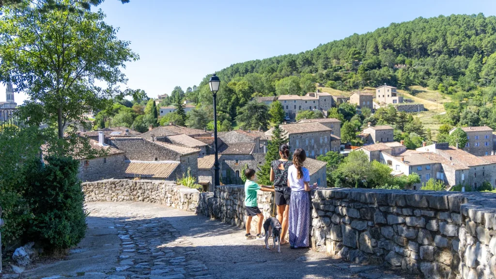 Famille visitant le village de caractère de Banne avec leur chien, en été