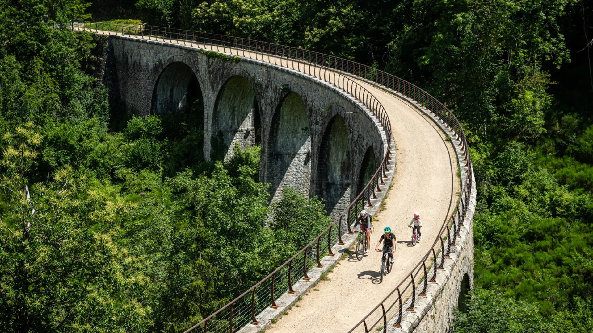 Famille à vélo sur la Dolce Via, dans la vallée de l'Eyrieux, en été