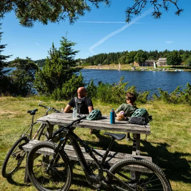 Grande traversée de l'Ardèche, deux cyclistes font une pause au lac de Devesset, en été