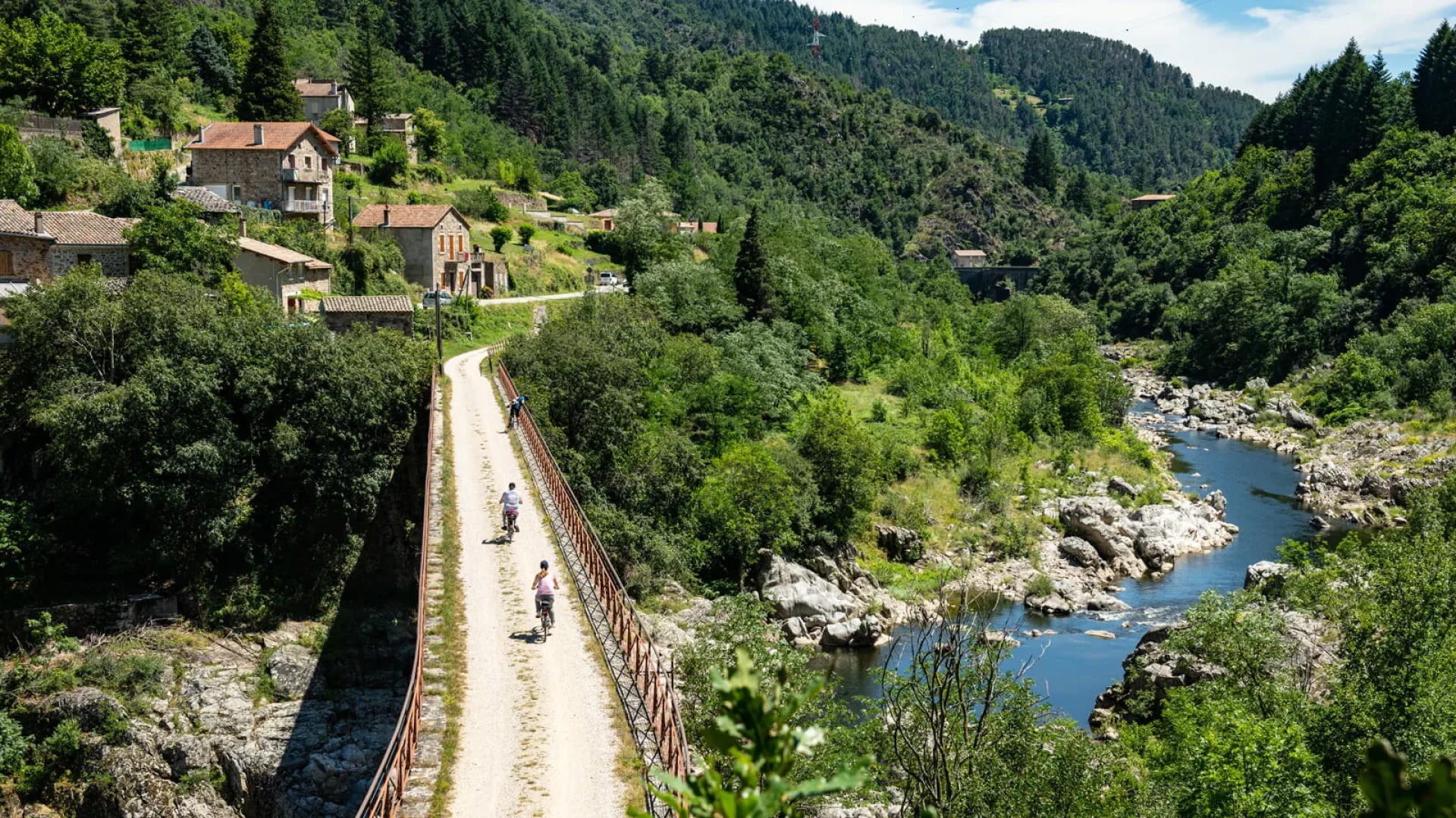 Personnes à vélo sur la Dolce Via, dans la vallée de l'Eyrieux, en été