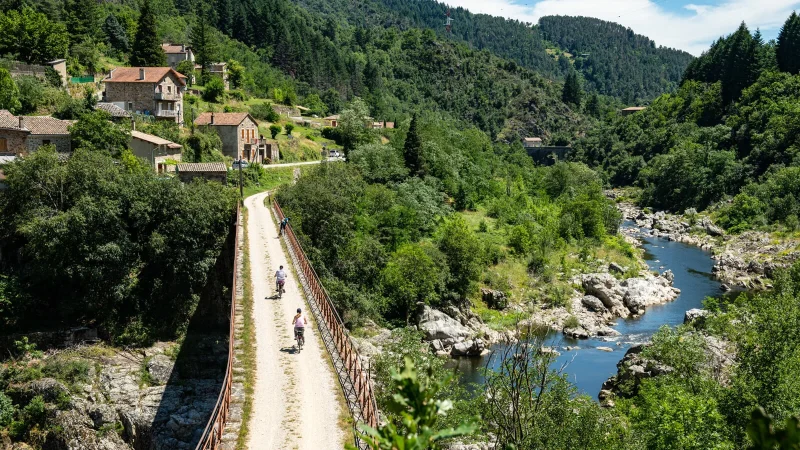 Personnes à vélo sur la Dolce Via, dans la vallée de l'Eyrieux, en été