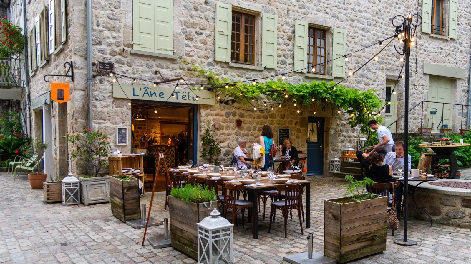Terrasse avec clients du restaurant l'Âne Têtu dans le village de caractère de Désaignes