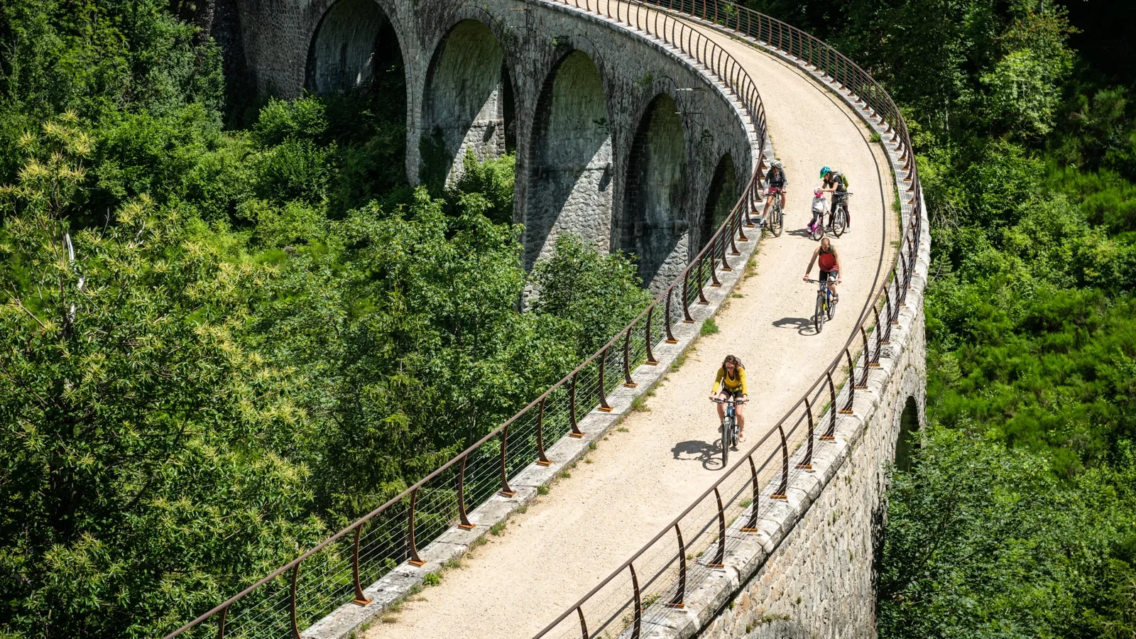 Famille à vélo sur la Dolce Via, dans la vallée de l'Eyrieux, en été