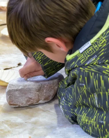 Enfant participant à une animation de l'Aven Orgnac : création de bijoux