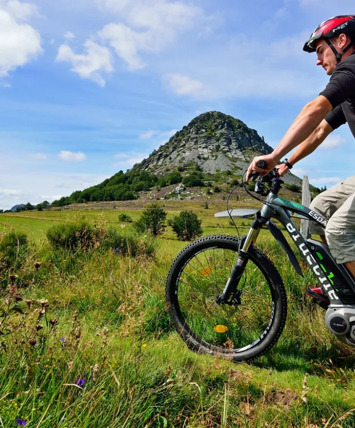 Hommes à vélo à assistance électrique devant le Mont Gerbier de Jonc, en été