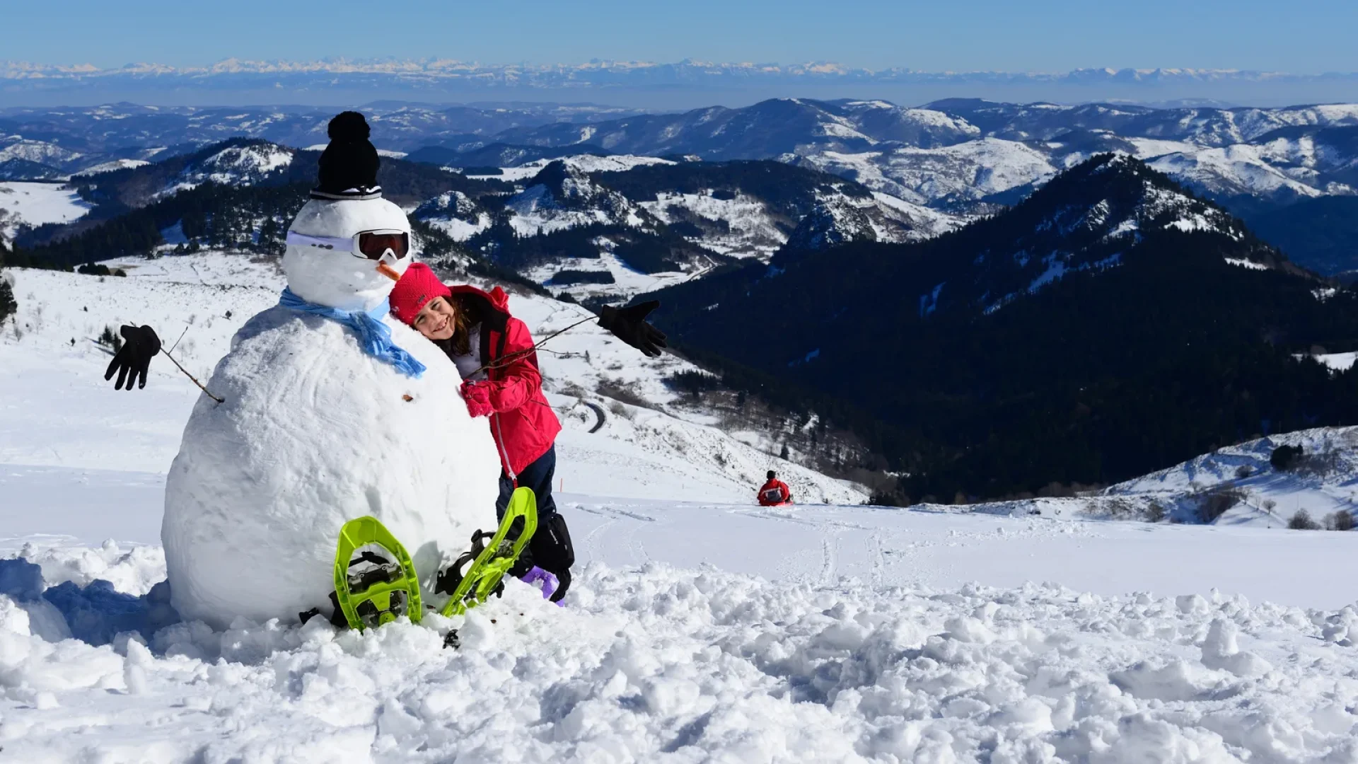 Fillette faisant un câlin à un bonhomme de neige en haut à la Croix de bauzon, en hiver