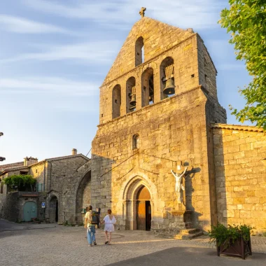 Couple devant l'église du village de caractère de Ailhon, en été