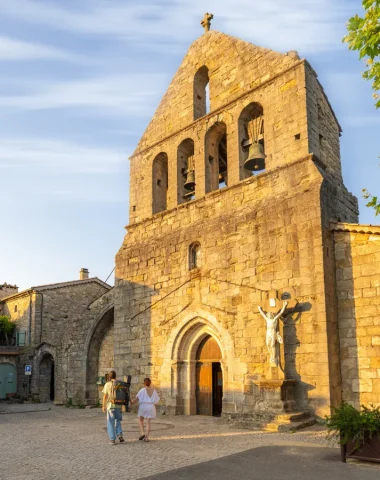 Couple devant l'église du village de caractère de Ailhon, en été