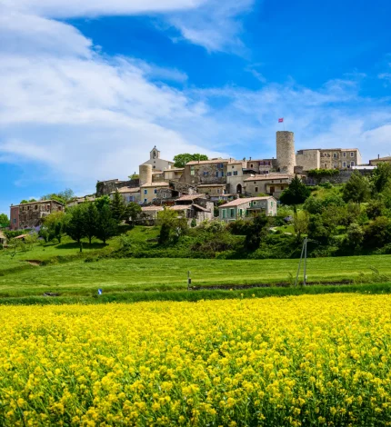 Village de caractère de Saint-Vincent-de-Barrès derrière un champ de Colza, au printemps