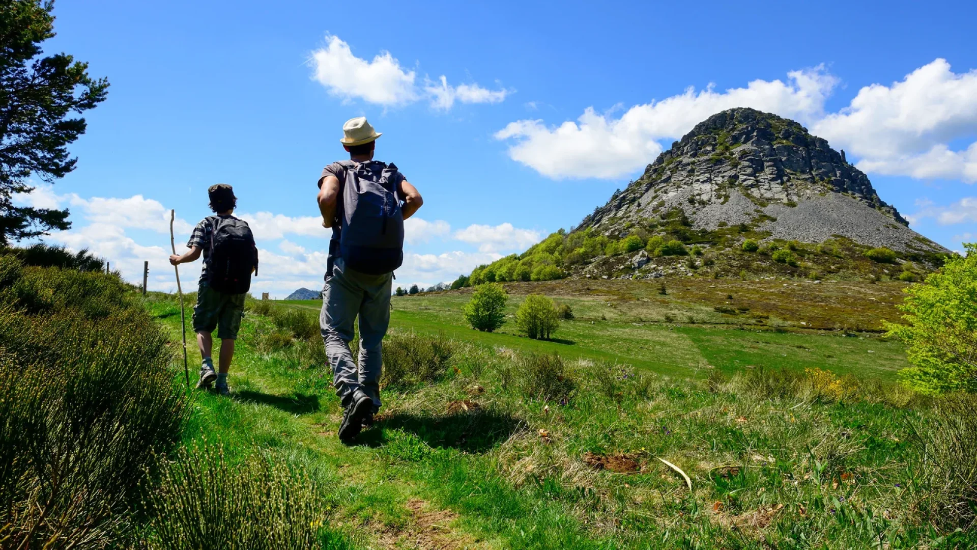 Un homme et son fils randonnant devant le Mont Gerbier de Jonc au printemps