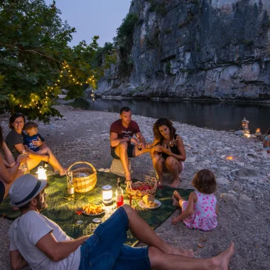 Famille partageant un pique-nique au bord de l'eau, lors d'une soirée d'été