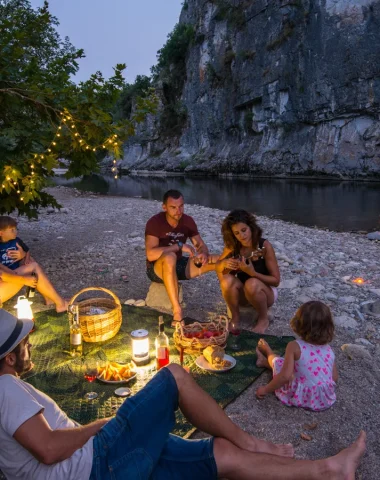 Famille partageant un pique-nique au bord de l'eau, lors d'une soirée d'été