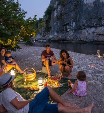 Famille partageant un pique-nique au bord de l'eau, lors d'une soirée d'été