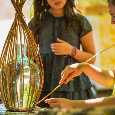 Femme pratiquant la vannerie sous le regard d'une enfant