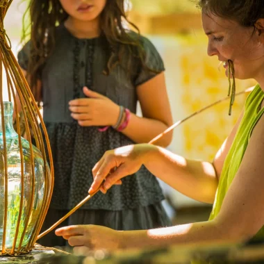 Femme pratiquant la vannerie sous le regard d'une enfant