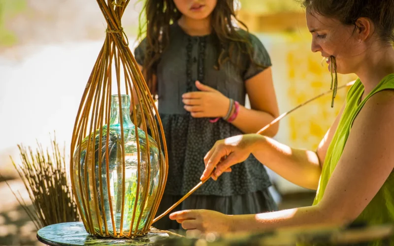Femme pratiquant la vannerie sous le regard d'une enfant