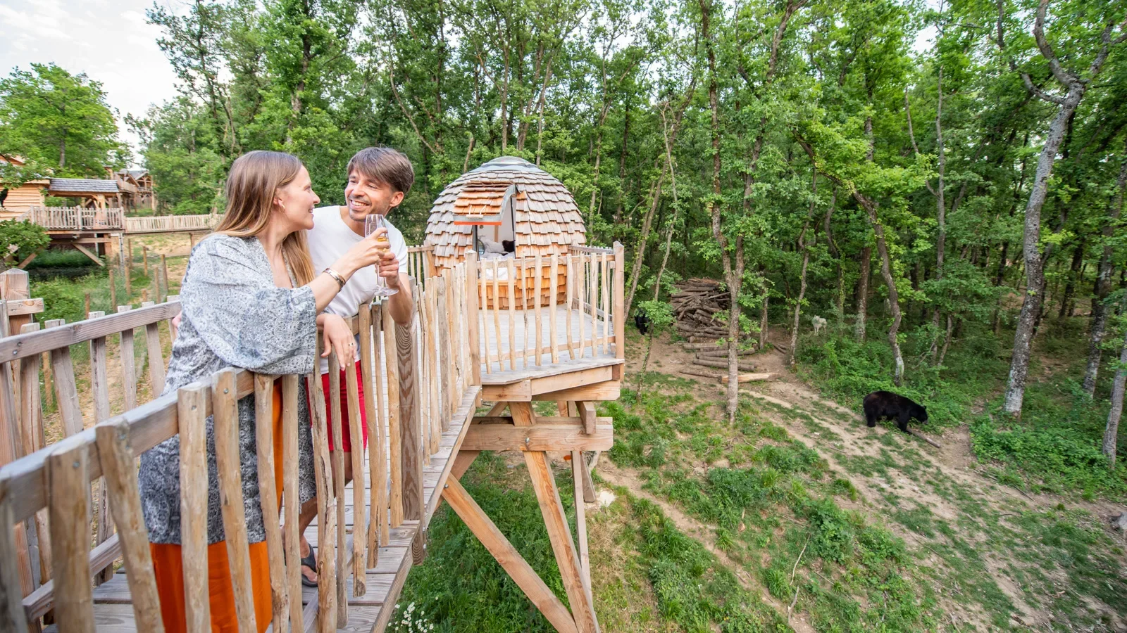 Couple trinquant dans un hébergement insolite : les "Cabanes perchées" du Safari de Peaugres, au dessus des loups et des ours