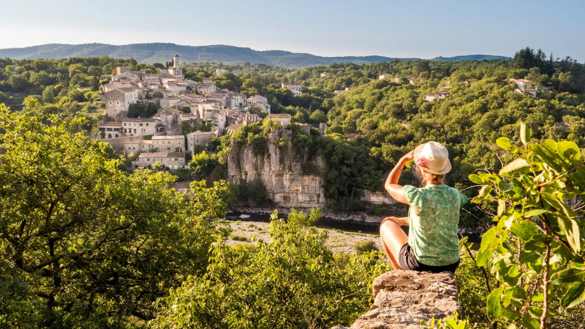 Femme observant le village de caractère de Balazuc, en été