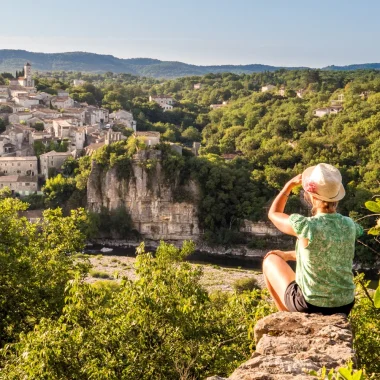 Femme observant le village de caractère de Balazuc, en été