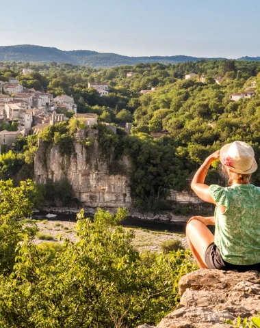 Femme observant le village de caractère de Balazuc, en été