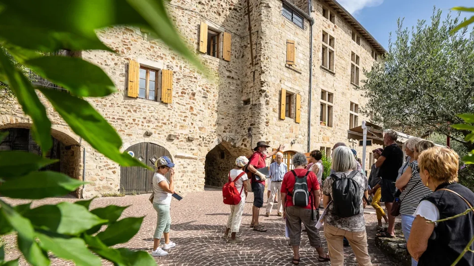 Groupe suivant une visite guidée au village de caractère de Vinezac en été