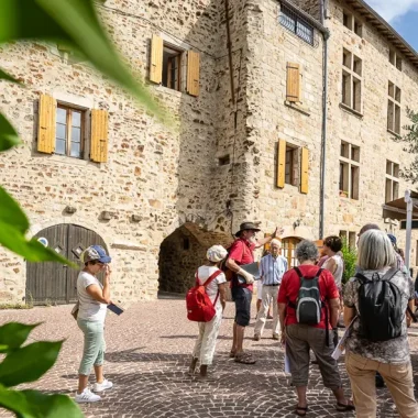 Groupe suivant une visite guidée au village de caractère de Vinezac en été