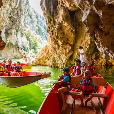 Famille faisant une balade en barque avec les Bateliers de l'Ardèche en été, au Pont d'Arc, dans les Gorges de l'Ardèche
