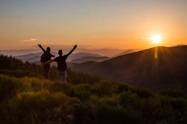 Couple saluant le coucher de soleil et la fin de leur randonnée en été