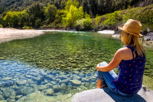 Femme se détendant au bord de l'eau, dans la vallée de l'Ibie, au printemps