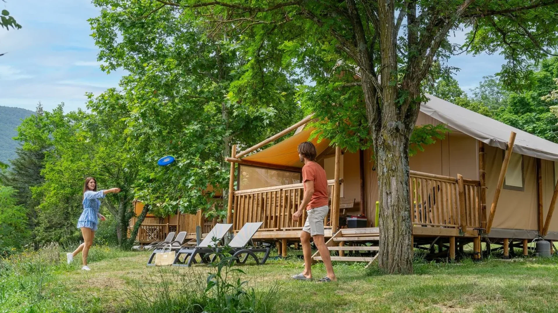 Couple se détendant devant leur tente aménagée dans le camping "Les Jardins de Privas", en été