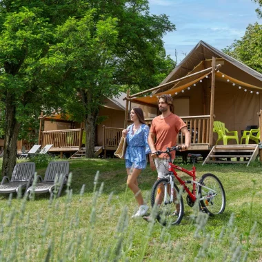 Couple partant en balade, avec un vélo, dans le camping 