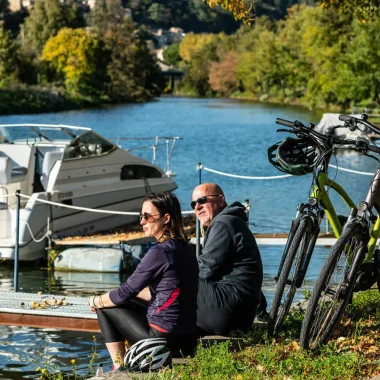 Couple faisant une pause au bord de la ViaRhôna vers Charmes-sur-Rhône, auprès de leurs vélos à assistance électrique, en automne