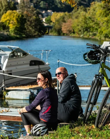 Couple faisant une pause au bord de la ViaRhôna vers Charmes-sur-Rhône, auprès de leurs vélos à assistance électrique, en automne
