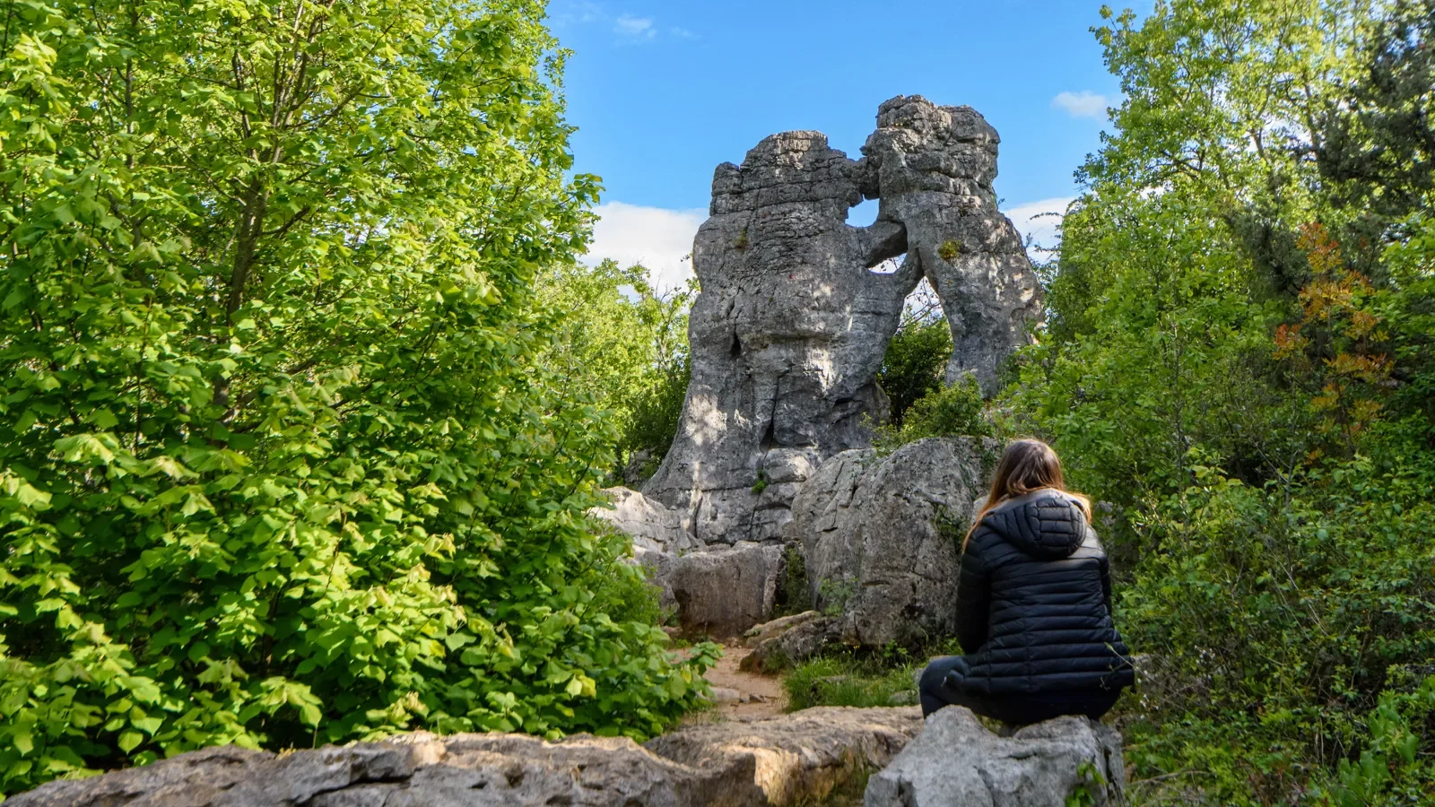Femme observant "l'ours et le lion" du Bois de Païolive au printemps
