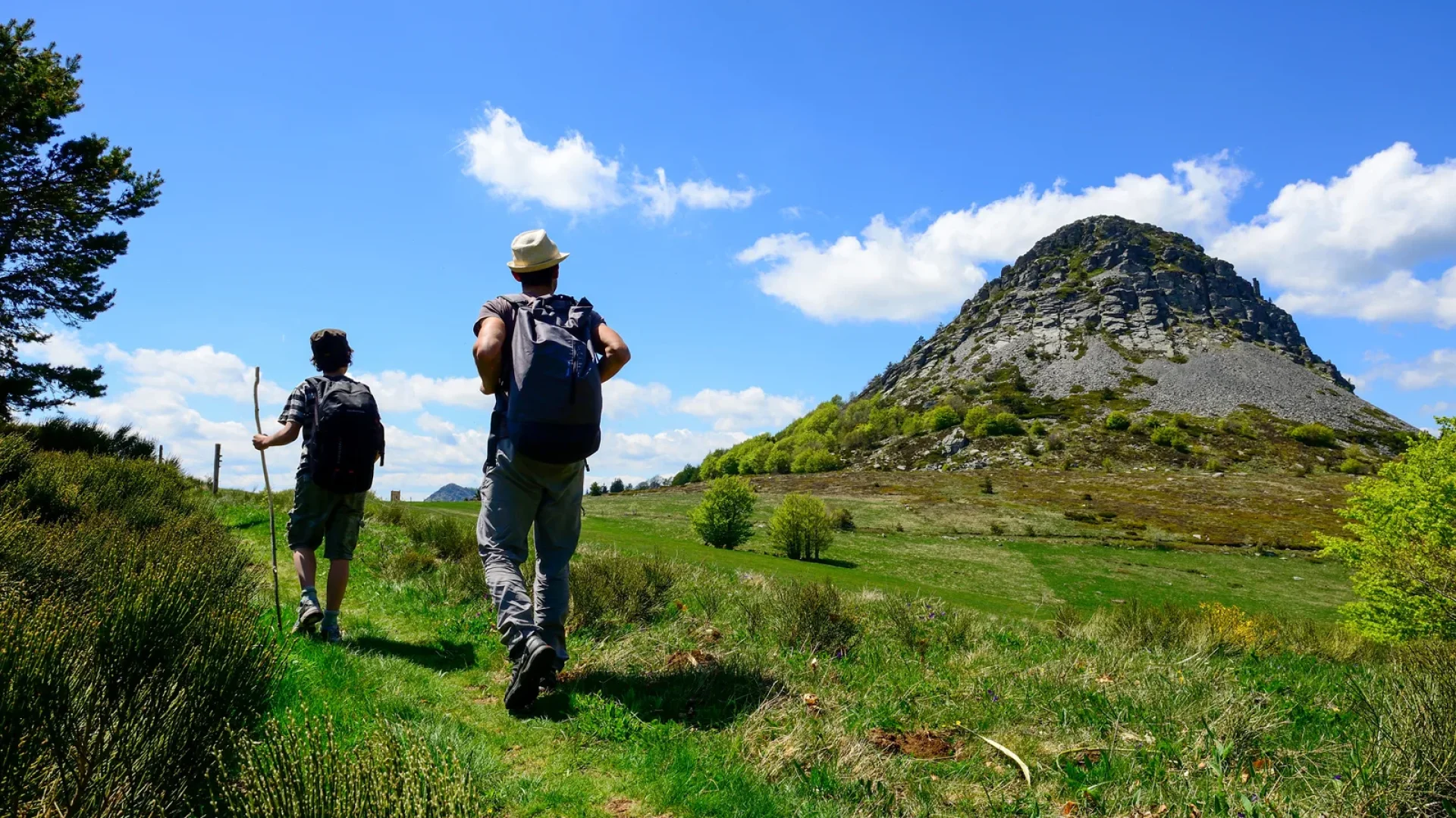 Un homme et son fils randonnant devant le Mont Gerbier de Jonc au printemps