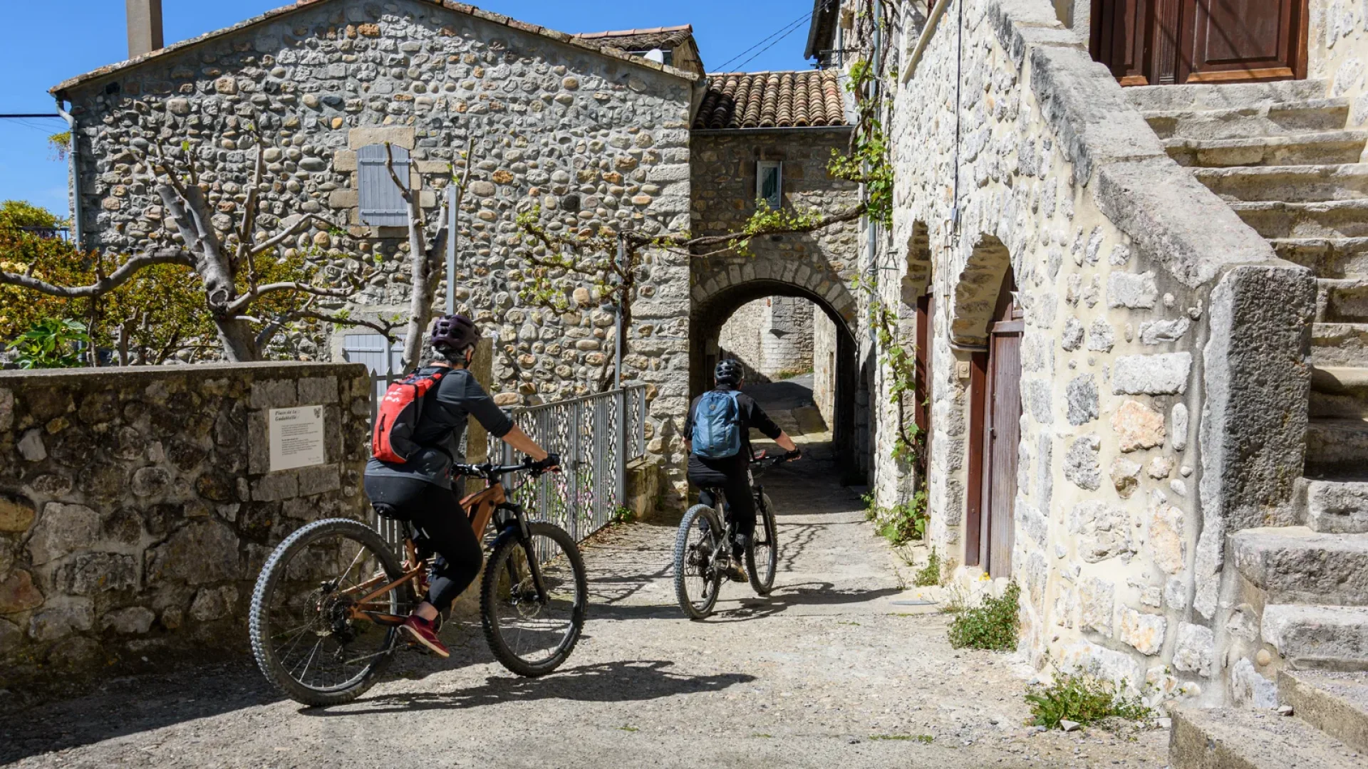Couple à vélo dans le village de caractère de Vogüé, au printemps