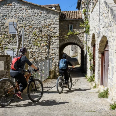 Couple à vélo dans le village de caractère de Vogüé, au printemps
